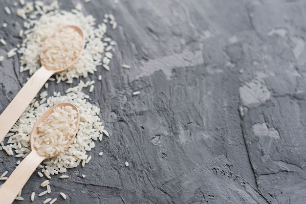 Free photo close-up of wooden spoon filled with rice over grey cement background