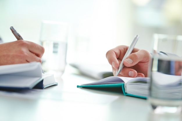 Free photo close-up of workers writing with pen