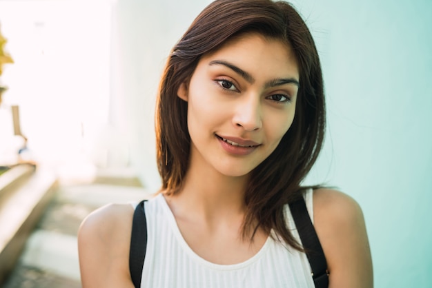 Free photo close-up of young brunette latin woman smiling outdoors in the street. urban concept.