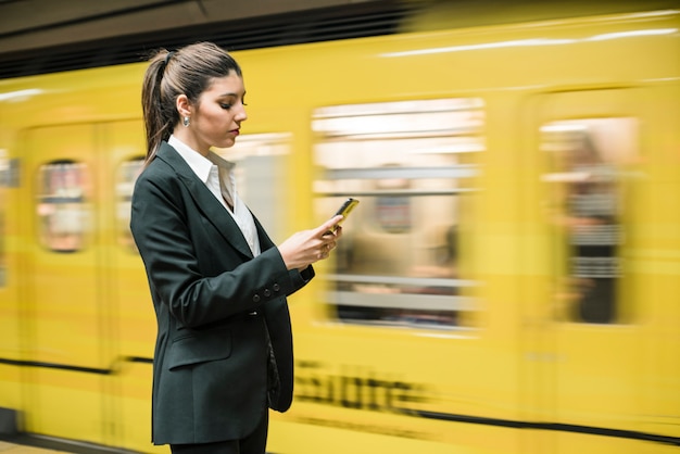 Close-up of a young businesswoman using mobile phone at the subway station