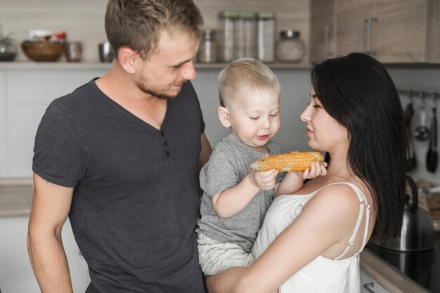 Close-up of young couple looking at his son eating corn