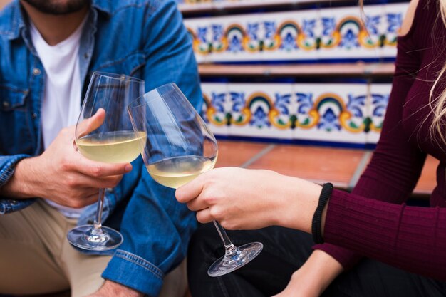 Close up of a young couple's hands clinking glasses of wine