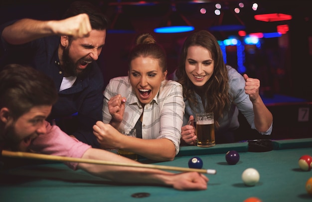 Close up on young friends having fun while playing pool game