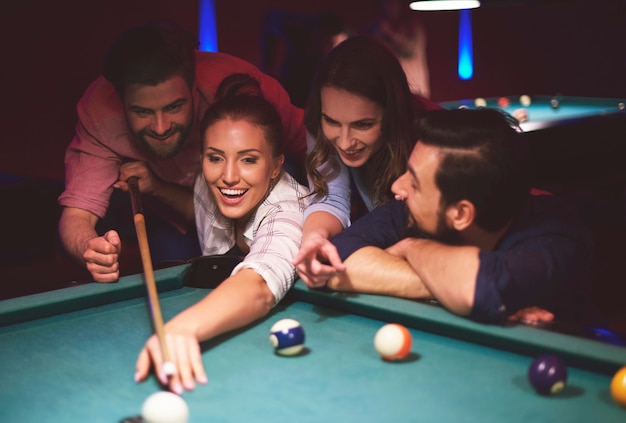 Close up on young friends having fun while playing pool game