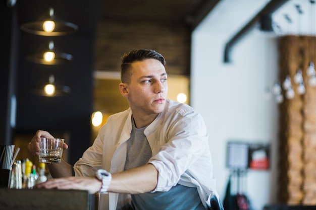 Close-up of young man holding glass of whisky in the bar