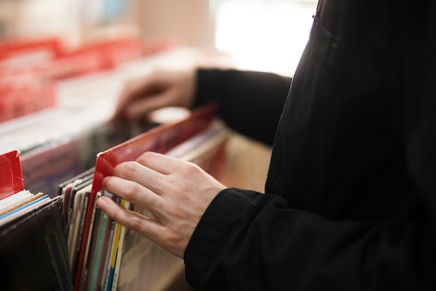 Free photo close-up young man looking for vinyls in store