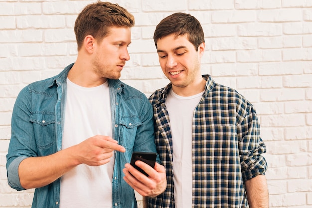 Close-up of a young man showing something on mobile phone to his friend