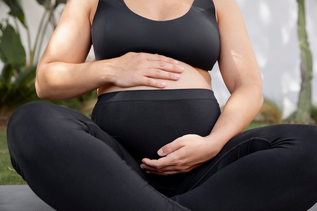 Free Photo close up on young pregnant woman doing yoga