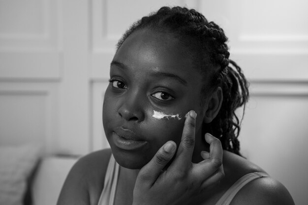 Close up young woman applying face cream