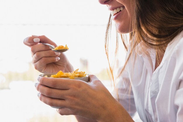 Close-up of young woman eating cornflakes with spoon