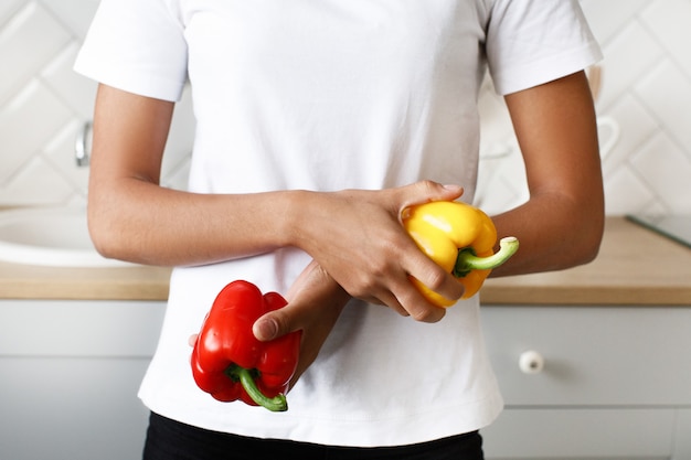 Free Photo close up, young woman holds two pepper yellow and red