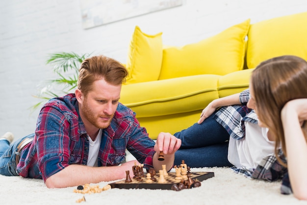 Close-up of young woman looking at man playing the chess game