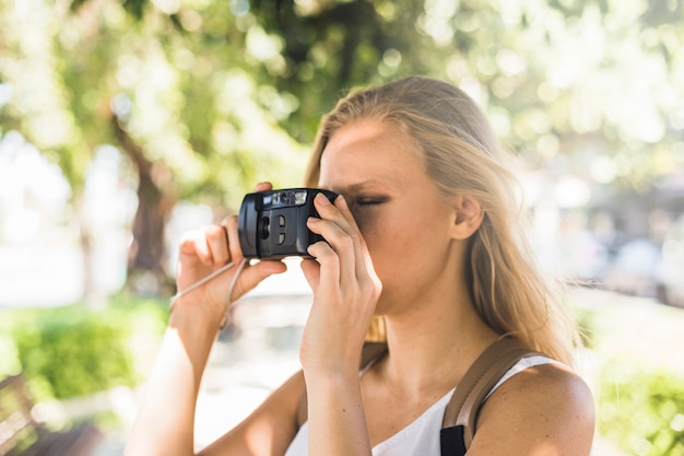 Close-up of young woman photographing with modern digital camera