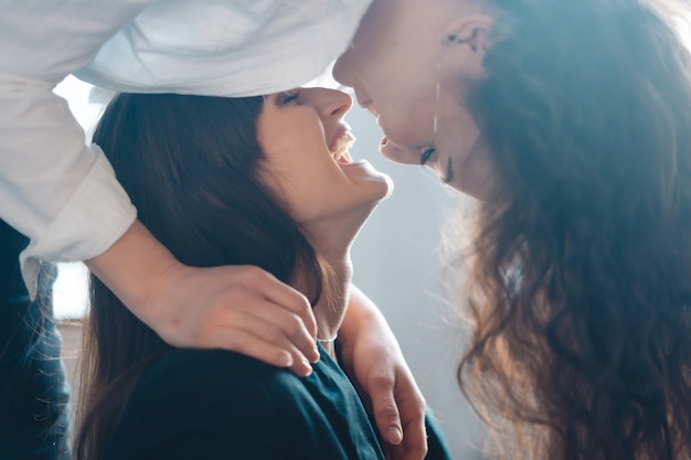 Free photo close up young woman thoughtfully kissing woman at home