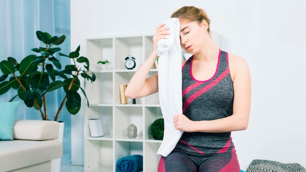 Free Photo close-up of young woman wiping the sweat with white towel in the living room