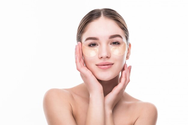 Close-up of a young woman with patches under eyes from wrinkles and dark circles isolated on white wall