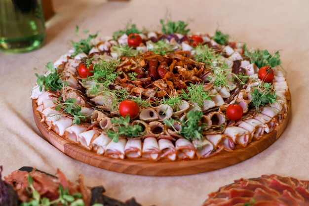 Free photo close view of appetizers on circle wooden plates full sliced different types of dried meat decorated by fresh tomato and greens served to table dinner party