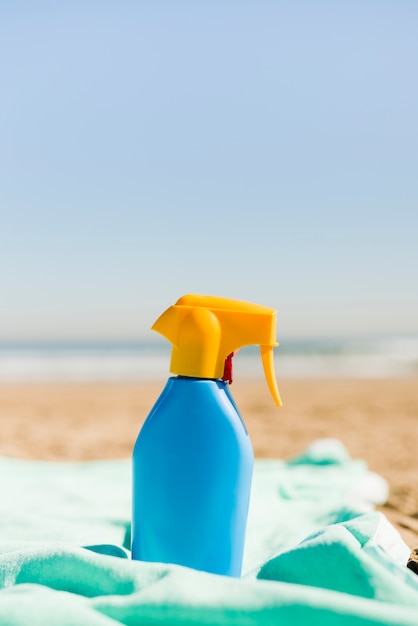 Free photo closed blue sunscreen cosmetics container on turquoise blanket at beach