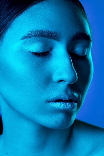 Free Photo closed eyes. beautiful east woman's portrait isolated on gradient studio background in neon, monochrome. female brunette model. concept of human emotions, facial expression, sales, ad, fashion and bea