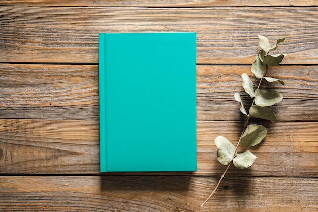 Closed green book on wooden background top view