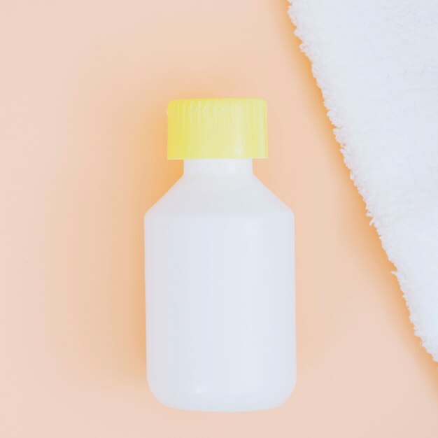 Closed yellow bottle cap with white napkin on beige background