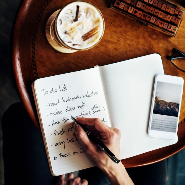 Free Photo closeup aerial view of hand writing to do list at cafe