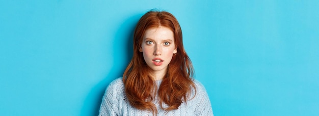 Free Photo closeup of amazed redhead girl staring at camera with complete disbelief standing shocked against bl