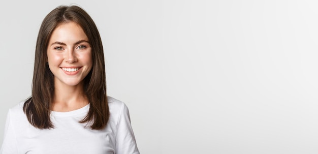 Closeup of attractive brunette girl smiling happy standing white background