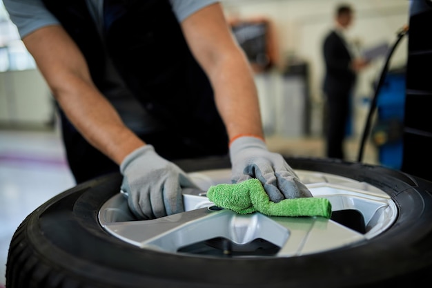 Closeup of auto mechanic cleaning car tire while working in auto repair shop