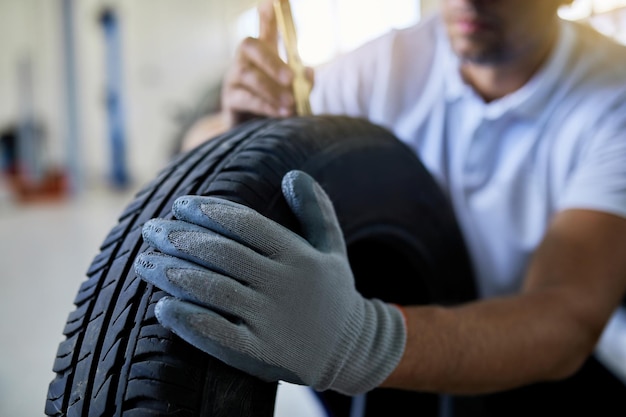 Free photo closeup of auto repairman measuring depth of car tire in auto repair shop