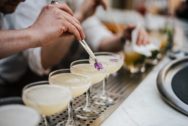 Closeup of a barman making margaritas with five glasses set in line