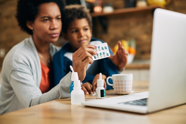 Closeup of black mother consulting with a doctor online about medicine for her son