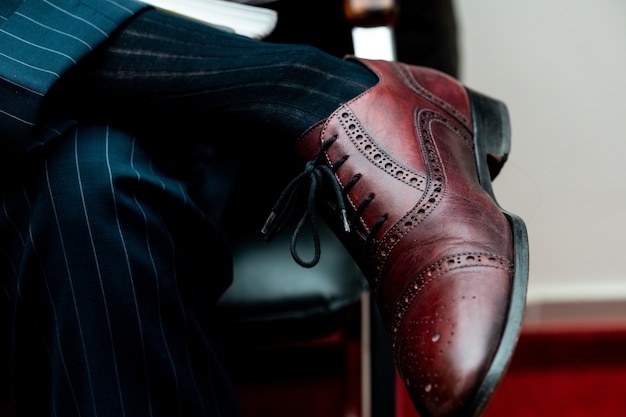 Free photo closeup of a brogue shoe on a person sitting with crossed legs under the lights