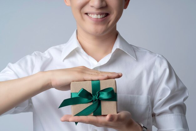 Closeup business communication ideas concept with asian attractive male casual tshirt hand hold brown present gift box smile and happiness hand gesture pose present point show joyful moment