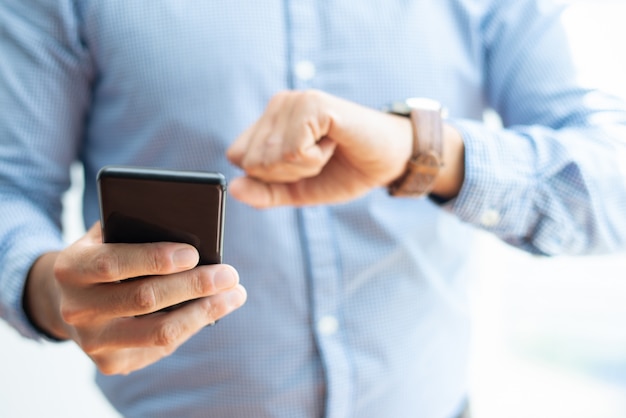 Free photo closeup of business man holding smartphone and checking time