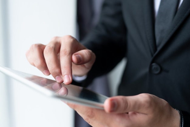 Closeup of business man holding and using tablet computer