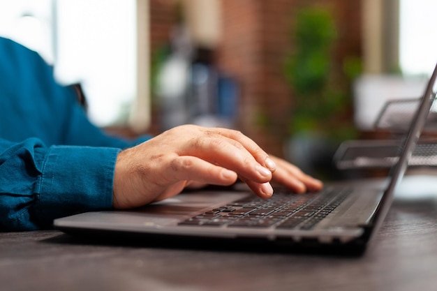 Closeup of businessman hand analyzing management graphs typing company strategy on laptop keyboard working at marketing project. Executive manager planning business investment in startup office