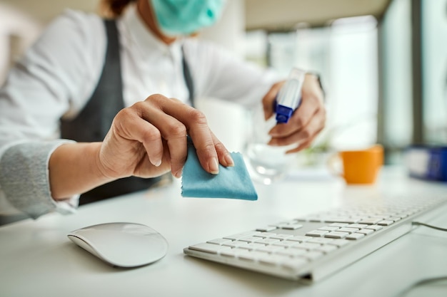 Free photo closeup of businesswoman disinfecting computer keyboard in the office