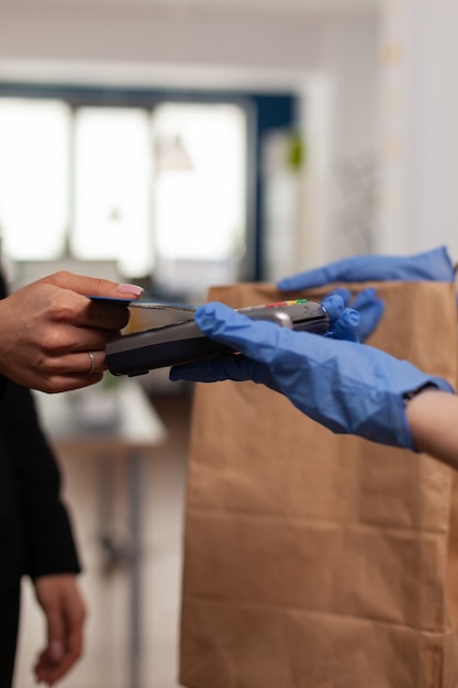 Free photo closeup of businesswoman paying takeaway food order with credit card using pos contactless service during takeout lunchtime