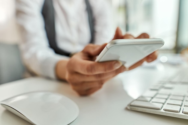 Closeup of businesswoman using smart phone and text messaging in the office