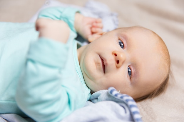 Closeup of calm sweet baby lying on bed cover