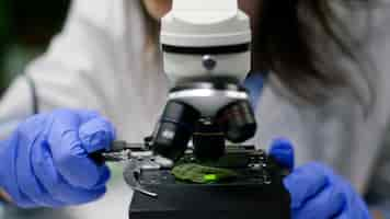 Free photo closeup of chemist researcher hands looking at leaf sample using microscope observing genetic mutation on plant