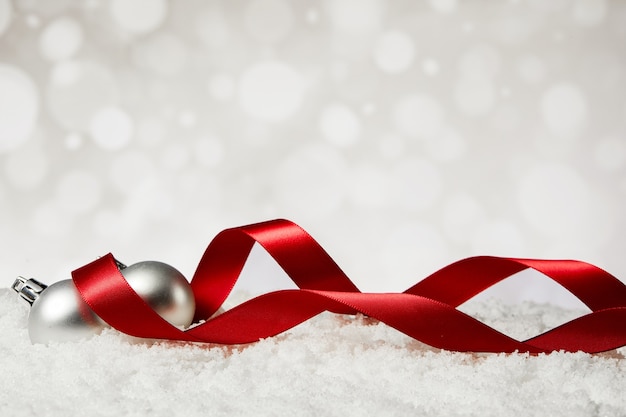 Closeup of Christmas ornaments with red ribbons on fake snow