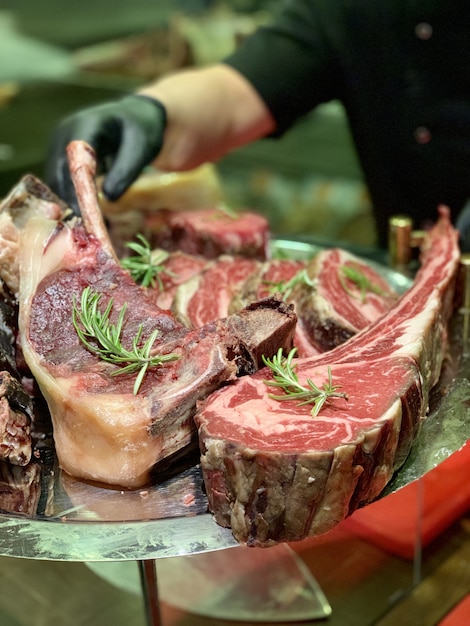 Free photo closeup of cooked red meat on a metal plate with the chef in the background