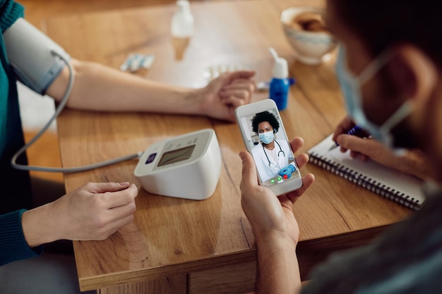 Free photo closeup of couple measuring blood pressure and having video call with their doctor from home