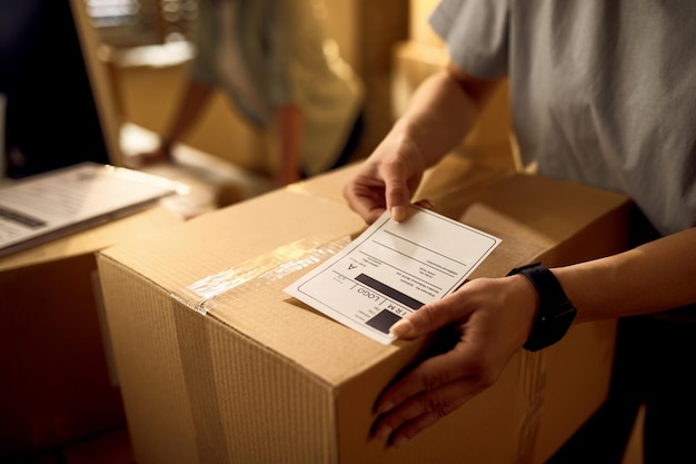 Free Photo closeup of courier attaching address label on a package while working in the office