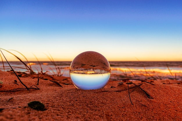 Free Photo closeup of a crystal ball on the beach with the surroundings reflecting on it