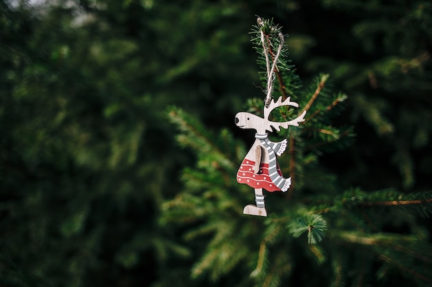 Free Photo closeup of a cute wooden deer-shaped christmas ornament hanging from a pine tree