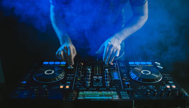 Free photo closeup of a dj working under the blue light