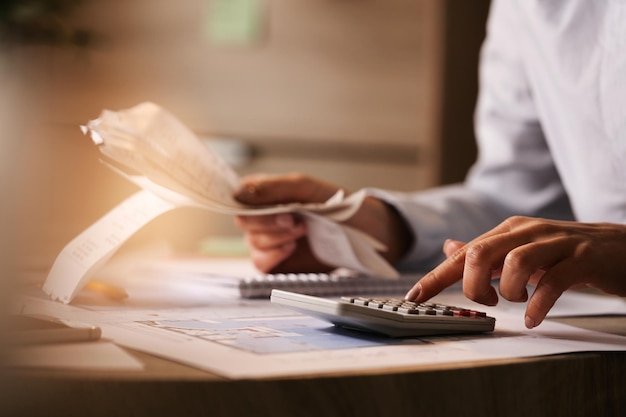 Closeup of economist using calculator while going through bills and taxes in the office